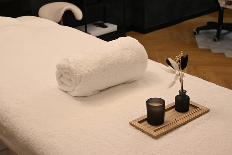 pexels photo 35884499 35884499 A serene spa massage table setup with a rolled towel, candle, and decorative vases in a relaxing environment.